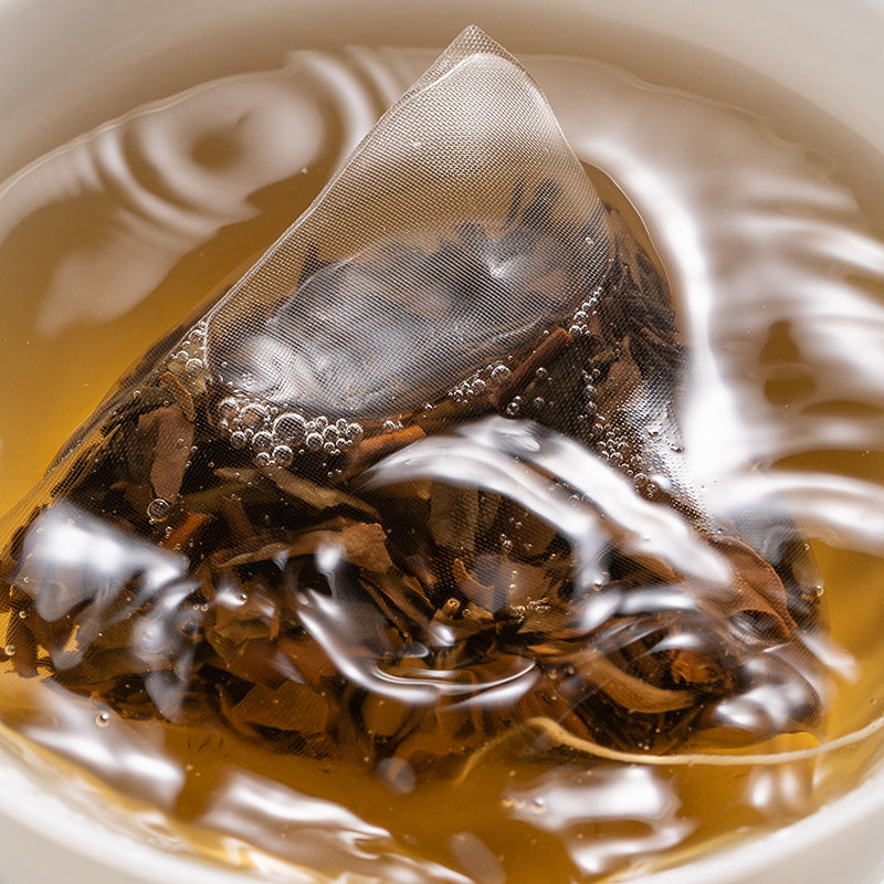 Tea bag steeping in a cup of tea with water droplets on the surface