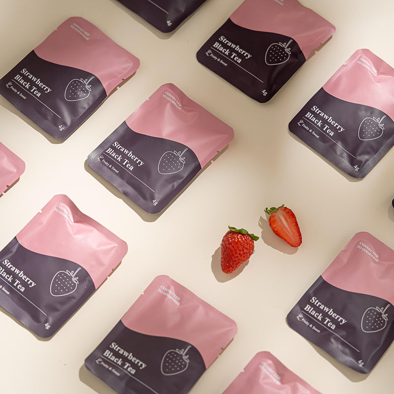 Strawberry black tea individual packages on a light background with strawberries