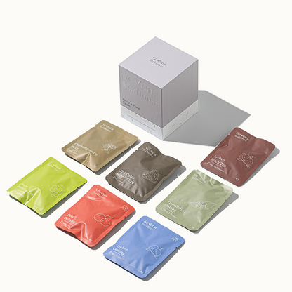A variety of individually wrapped tea bags in a range of fruity and floral flavors, displayed in front of their packaging box labeled Seven TeaHouse