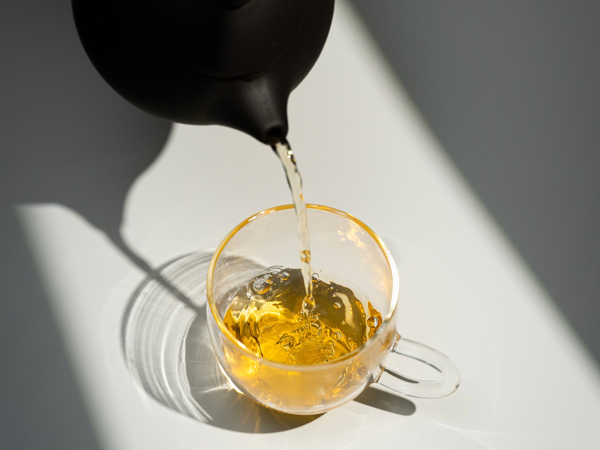 Pouring freshly brewed Golden Sprout Yellow Tea into a glass cup